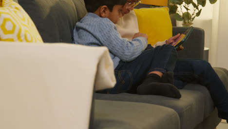 Zwei-Junge-Jungs-Sitzen-Zu-Hause-Auf-Dem-Sofa-Und-Spielen-Zusammen-Spiele-Oder-Streamen-Auf-Einem-Digitalen-Tablet-5